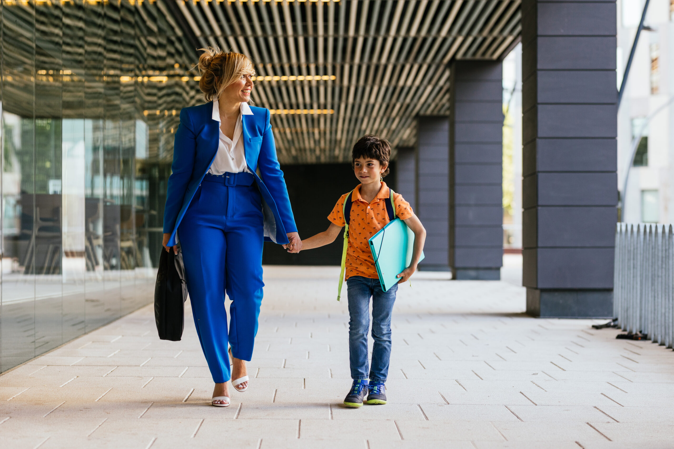 Boy carrying backpack happy to go to work with his mother after school.