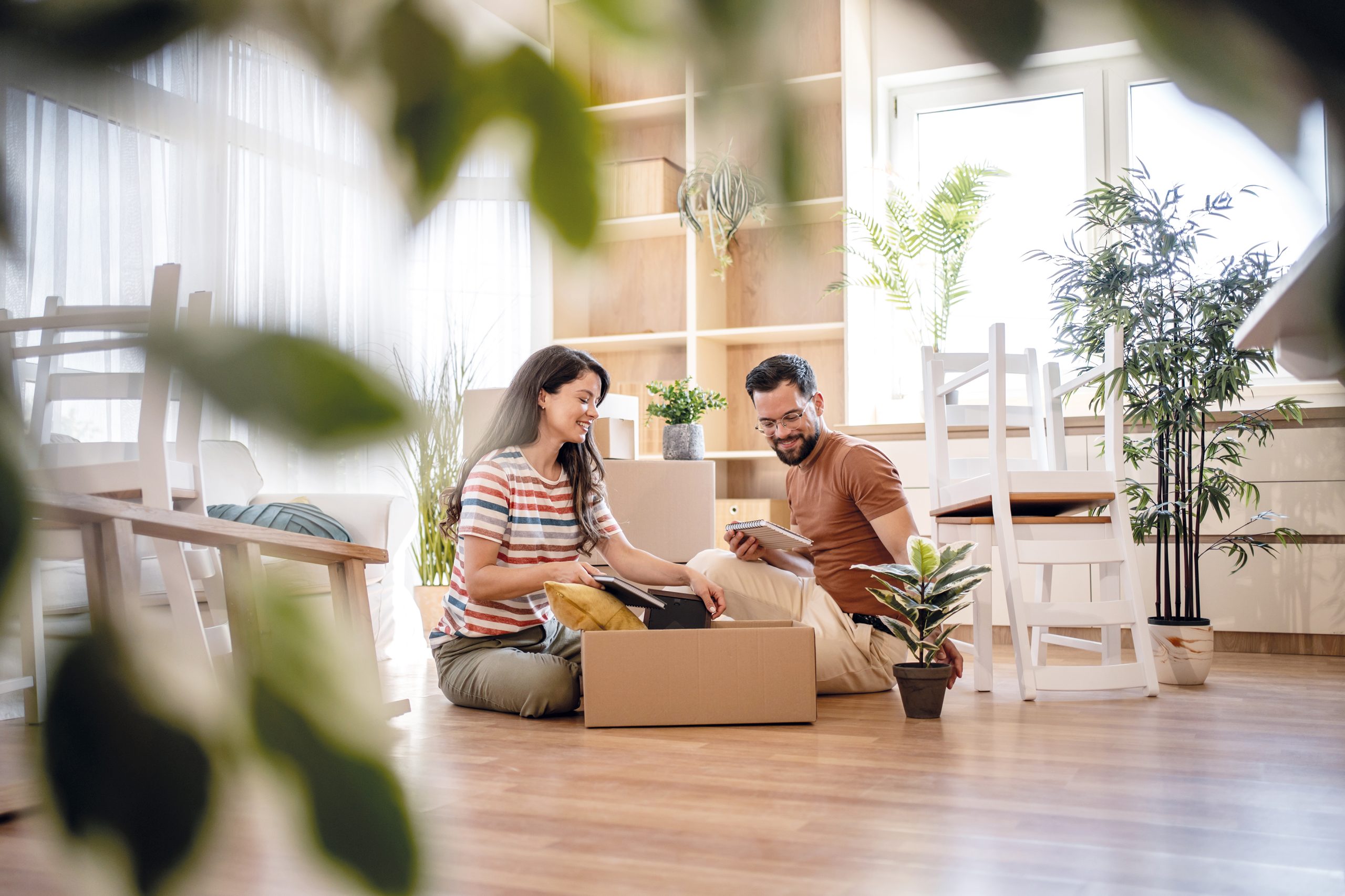 Happy couple unpacking boxes in new home after moving in
