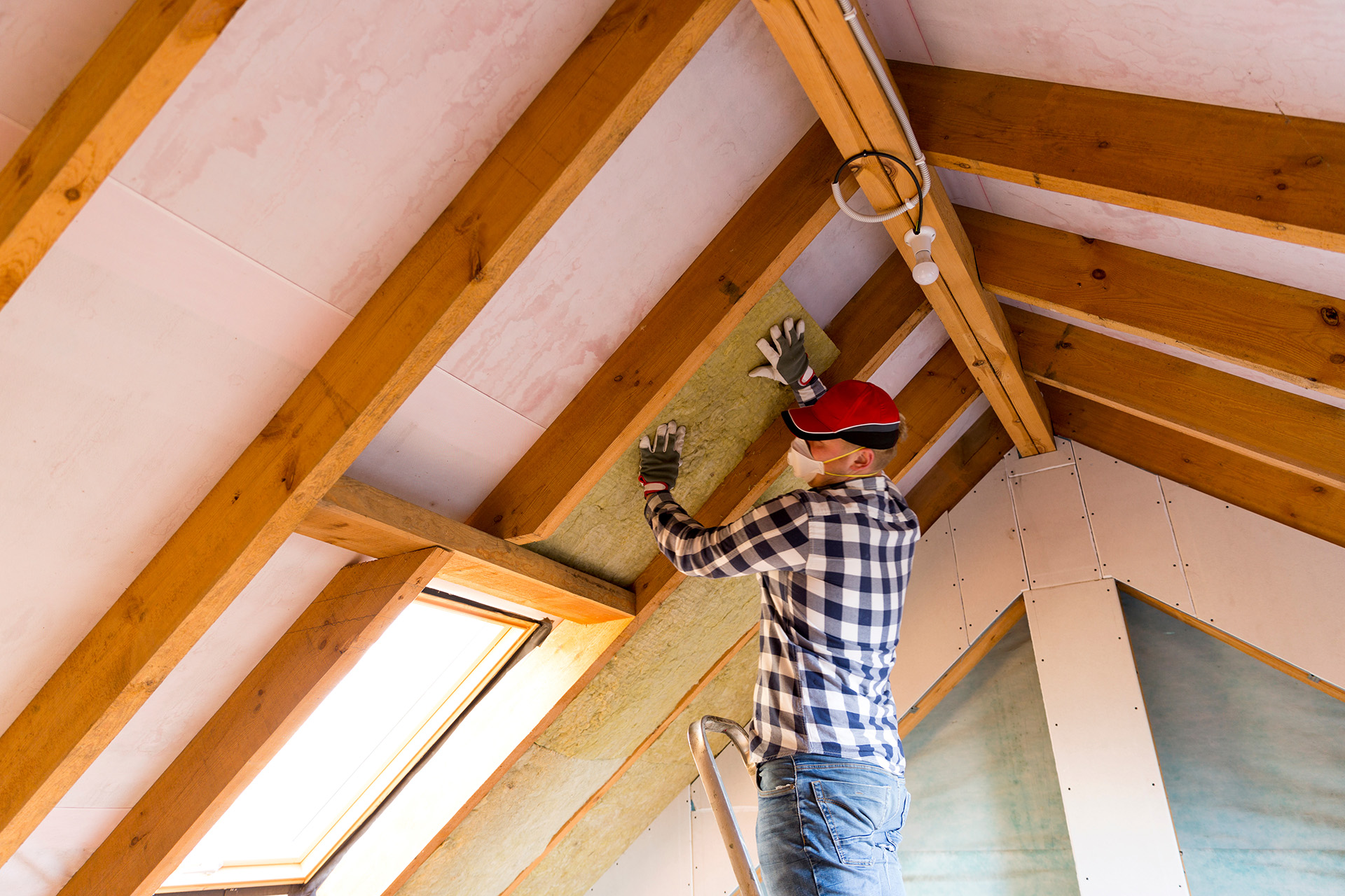 Man installing thermal roof insulation layer  - using mineral wo